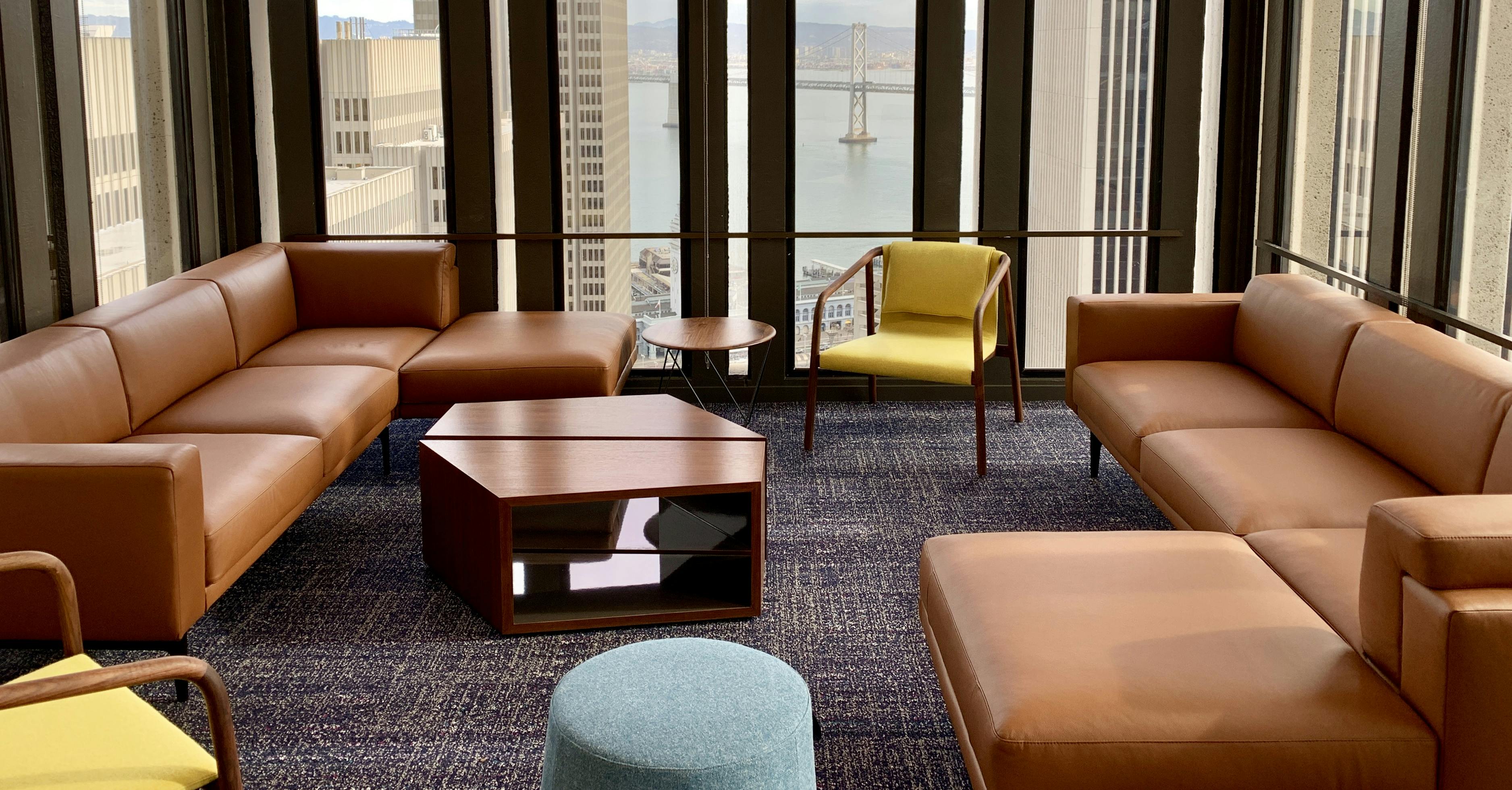 Lounge area from Nixon Peabody's San Francisco office, showing caramel-colored couches, a couple of yellow chairs, and a coffee table